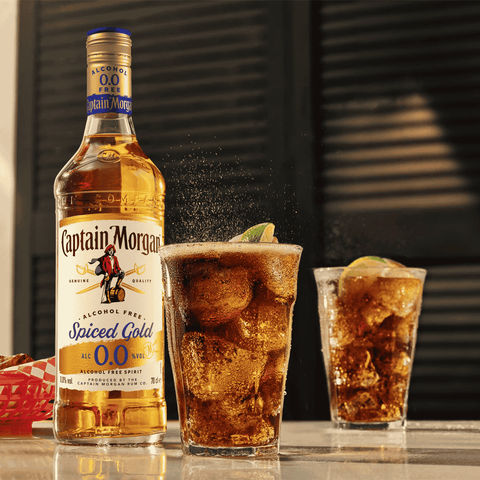 Captain Morgan Spiced Gold alcohol-free rum bottle with two glasses and cola