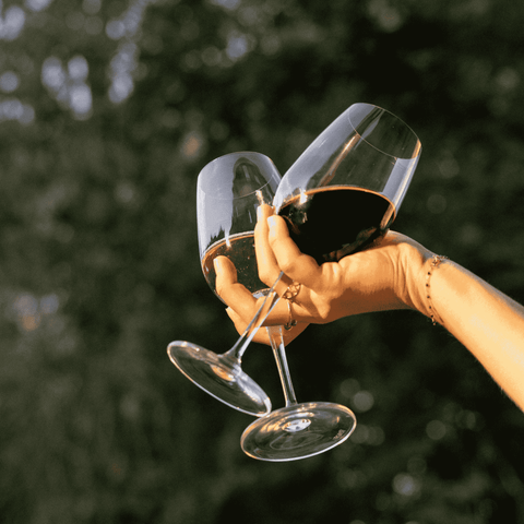 A hand holding wine glasses of non-alcoholic wine