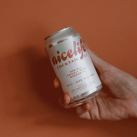 a person holding a blue and white can of NiceLIfe Cocktail Co. non-alcoholic Prickly Pear Margarita