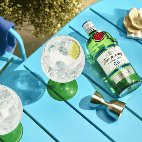 A bottle of Tanqueray 0.0 displayed on a blue table