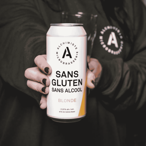 A person holding a can of Alchimiste Microbrasserie Gluten Free Non-Alcoholic Blonde
