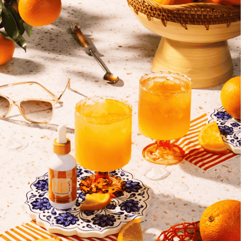 A bottle of Bliss Spritz Mushroom Mocktails by Ananda Elixirs, mixed into an orange spritz drink