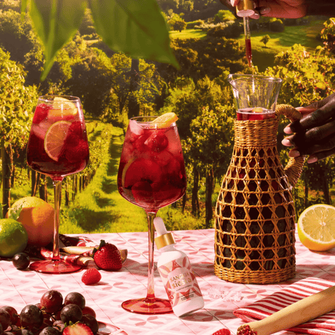 A bottle of Sangria Siesta Mushroom Mocktails being mixed into a pitcher of sangria