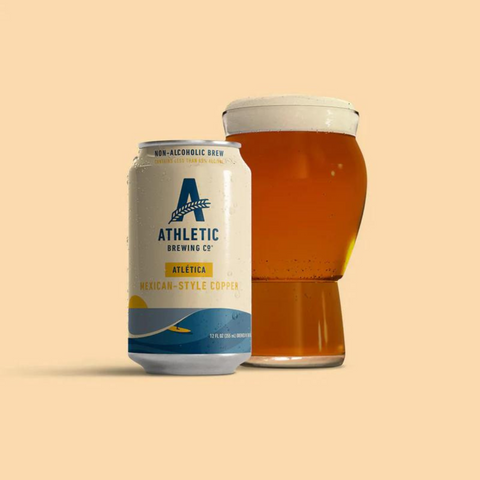 A can of Athletic Brewing Cerveza Atletica Light Copper non-alcoholic beer poured into a glass.