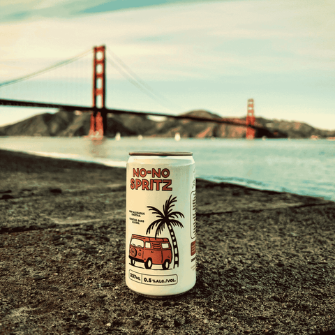 A can of No-No Spritz non-alcoholic cocktail displayed on a beach