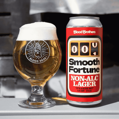 A can of Smooth Fortune Non-Alc Lager by Blood Brothers poured into a branded glass