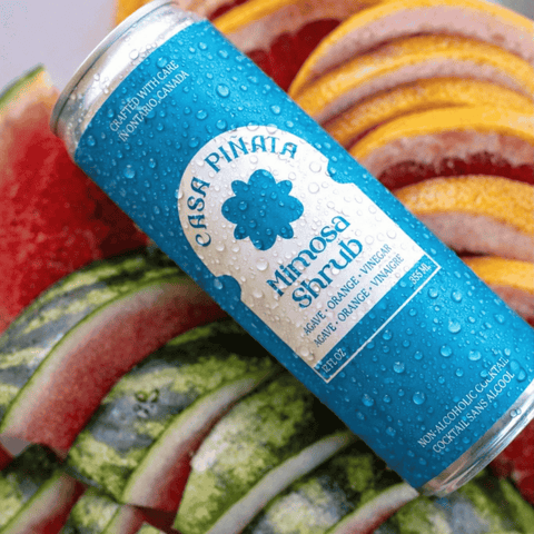 A blue can of Casa Pinata Mimosa Shrub displayed with fruit