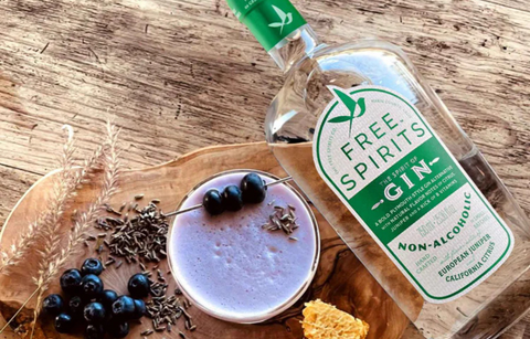 Bottle of Free Spirits Non-Alcoholic Gin on a wooden surface with a small dish and berries.