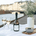 A bottle of Copenhagen BLÅ Sparkling Tea poured into Champagne flutes served with fruit