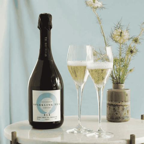 A bottle of Copenhagen BLÅ Sparkling Tea with two Champagne flutes