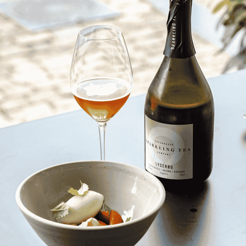 A bottle of Copenhagen LYSERØD Sparkling Tea poured into a flute and served with dessert