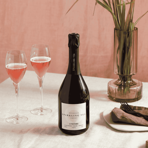 A bottle of Copenhagen LYSERØD Sparkling Tea poured into two flutes