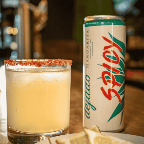 A can of Dejado non-alcoholic Spicy Margarita poured into a glass with a Tajin salted rim