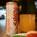 A can of Dejado non-alcoholic Spicy Paloma poured into a glass with a salted rim