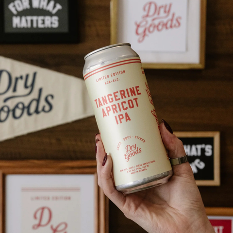 A person holding a can of Dry Goods non-alcoholic Tangerine Apricot IPA