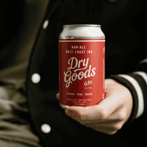 A person holding a can of Dry Goods West Coast IPA Non-Alcoholic Beer