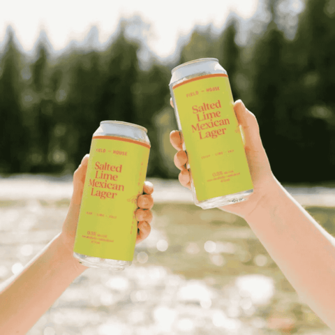Two hands holding cans of Field House non-alcoholic Salted Lime Mexican Lager