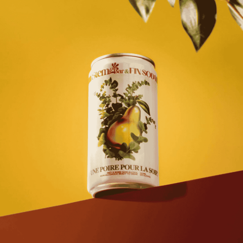 A can of Fin Soda Une Poire Pour la Soif! perched on a ledge with a yellow background