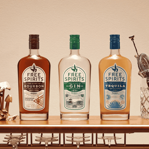 Three bottles of non-alcoholic spirits by Free Spirits displayed on a bar cart with glassware
