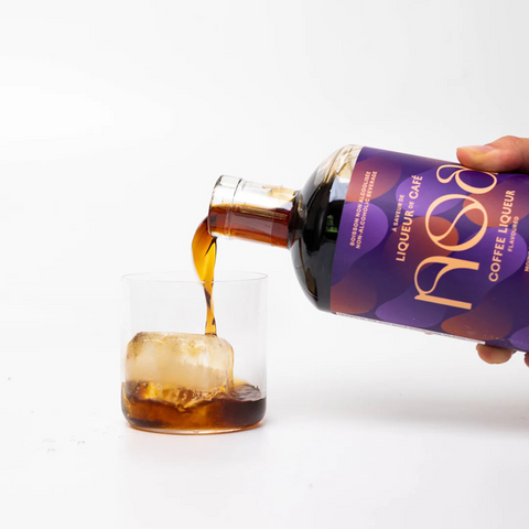 A bottle of NOA Non-Alcoholic Coffee Liqueur being poured over ice