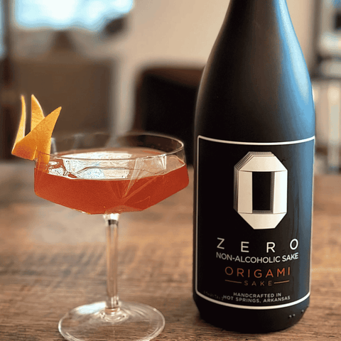 Bottle of Origami Zero Non-Alcoholic Sake with a cocktail on a wooden table
