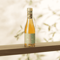 A bottle of Saicho Sparkling Hojicha Tea 200 mL on a wood shelf