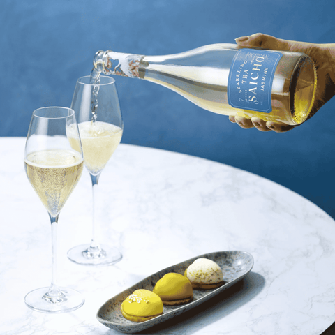 A boggle of Saicho Sparkling Jasmine Tea being poured into two glasses paired with dessert