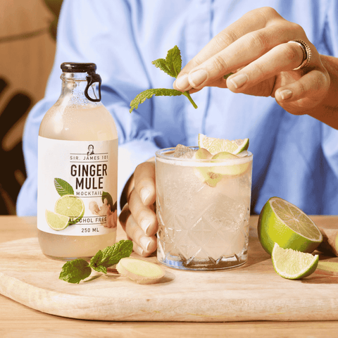 A bottle of Sir James 101 non-alcoholic Ginger Mule poured into a rocks glass and garnished with a mint sprig