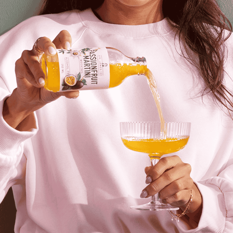 A bottle of Sir James 101 non-alcoholic Passionfruit Martini being poured into a cocktail glass