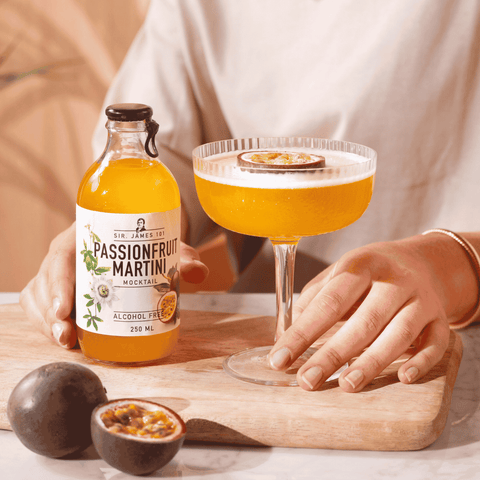 A bottle of Sir James 101 non-alcoholic Passionfruit Martini poured into a cocktail glass and garnished with a slice of passionfruit