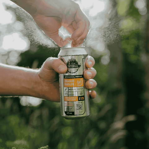 A person opening a can of Sober Carpenter Orange Radler