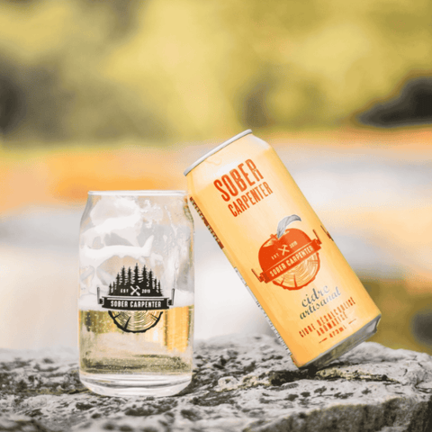 Can and glass of Sober Carpenter cider on a stone surface