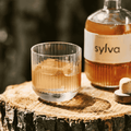 A bottle of Sylva ORCHARD non-alcoholic aged spirit poured into a glass with ice