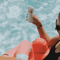 A person in  a pool holding a can of TOST Original Sparkling Tea