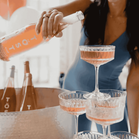 A bottle of TOST Rosé Sparkling White Tea being poured into a sparkling wine tower