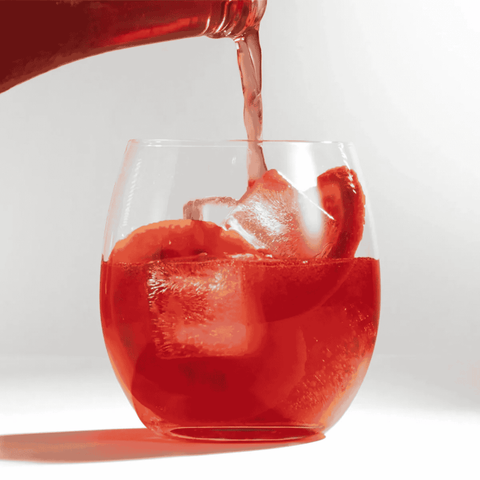 A Bottle of TOST Sangria being poured into a glass with ice and fruit