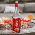 Bottle of Töst Sangria with two glasses filled with sangria on a patio table.